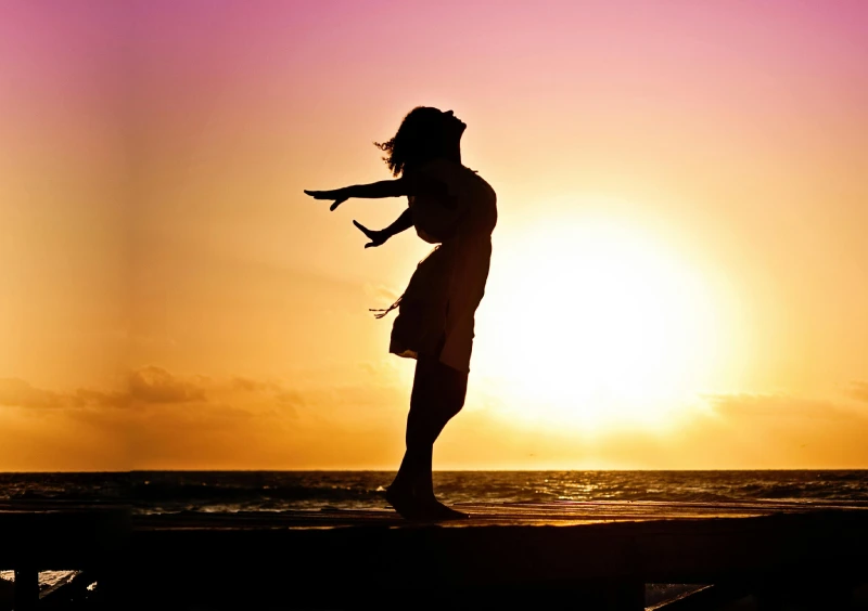 a woman's silhouette standing against the sun