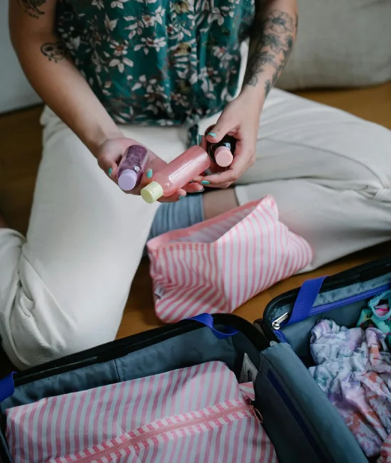 a woman holding bottles of skin care preparing for a trip