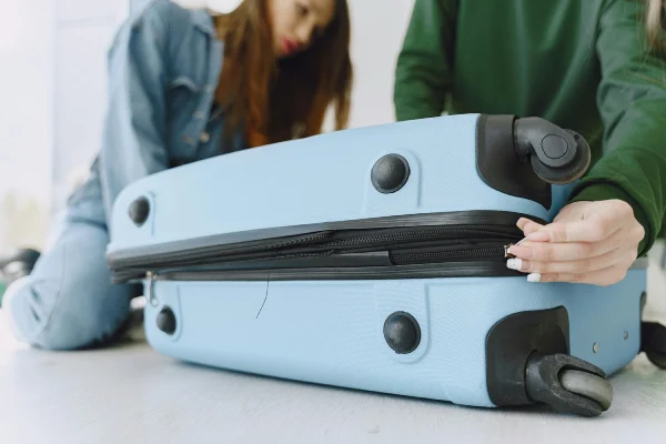 a woman trying to pack on her blue luggage