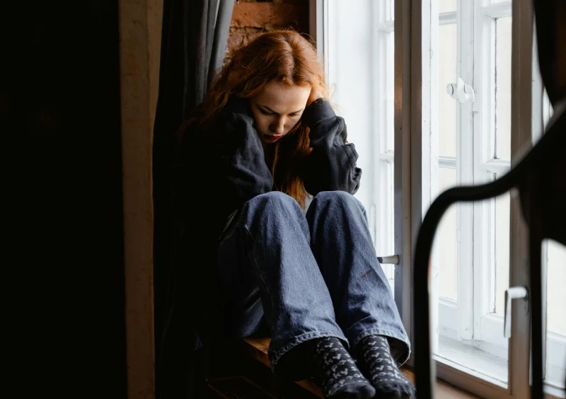 woman feeling sad, sitting at the window side