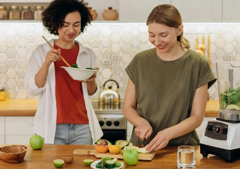 2 women preparing for a meal, with fruits around them, used for pcos for macros blog