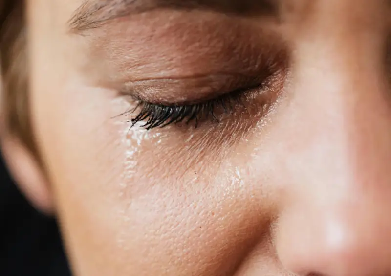 a close-up shot of a woman, crying, showing her left eye crying