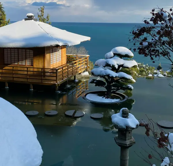 Brown Wooden House on Snow Covered Ground Beside Body of Water