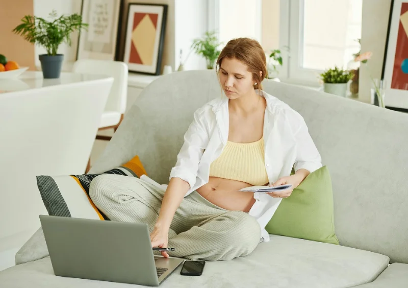 a pregnant woman looking for a work from home job in front of her laptop