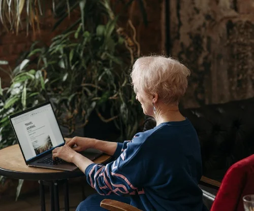 an old lady sitting on a table using a laptop